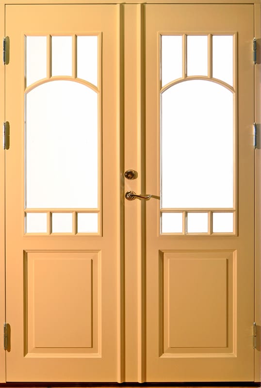 Ljusgul dubbeldörr med glasrutor i övre delen, dekorerade med spröjs som formar en båge överst och små rektanglar nederst. Nedre delen av dörrbladen har spegelpaneler.