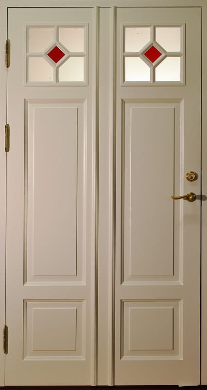 Ljus pardörr med små glasrutor upptill, röda diamantdetaljer och höga speglar nedtill.