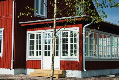 Röd fasad med spröjsade fönster och glasverandapartier, klassiska vita foder.