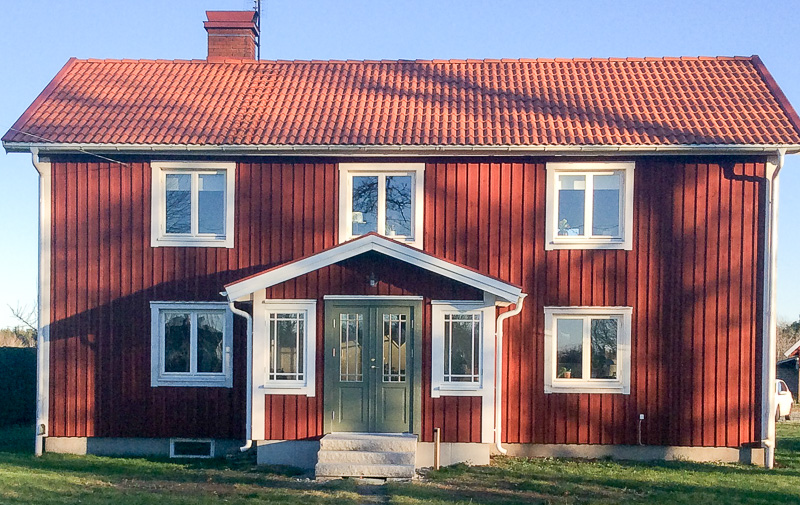 Ny veranda med glasade sidopartier och spröjsade fönster som släpper in ljus runt entrén.