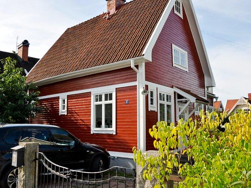 Efter renovering: samma gula hus med återställd träfasad, nya fönster och ny ytterdörr.