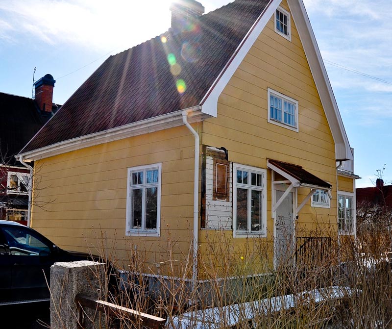 Före renovering: gult hus med äldre fasad och fönster, vy från gatan.