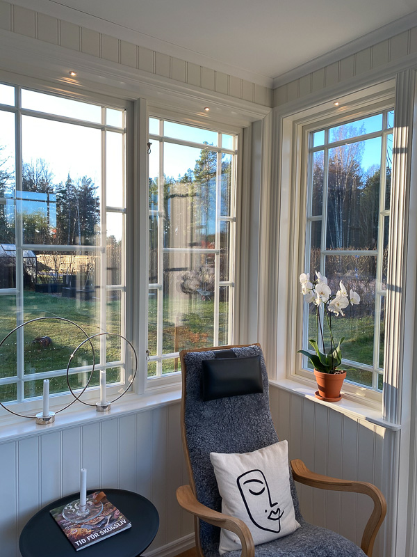 Spröjsade fönster med stora glasrutor som ger mjukt dagsljus i rummet.
