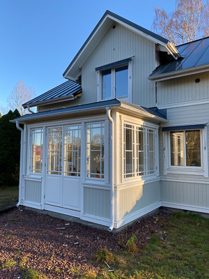 Spröjsade fönsterpartier och glasad dörr i veranda som släpper in mycket dagsljus.