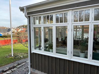 Entré med pardörr med spröjsade glasrutor och smala sidofönster som släpper in ljus.