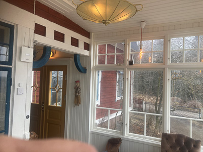 Spröjsade överljus och stora glasrutor i veranda som släpper in dagsljus.