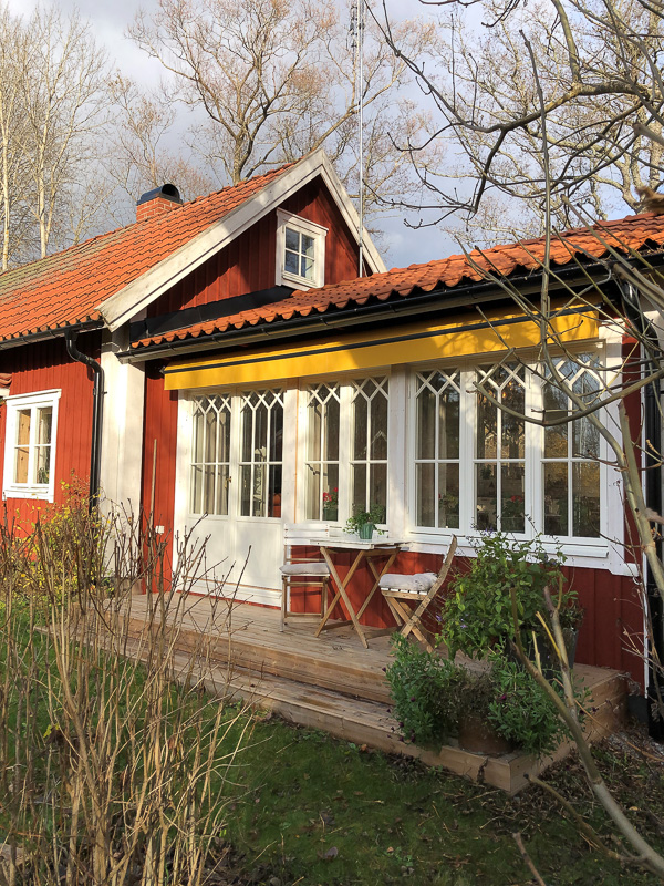 Veranda med stora glaspartier och spröjs som släpper in ljus.