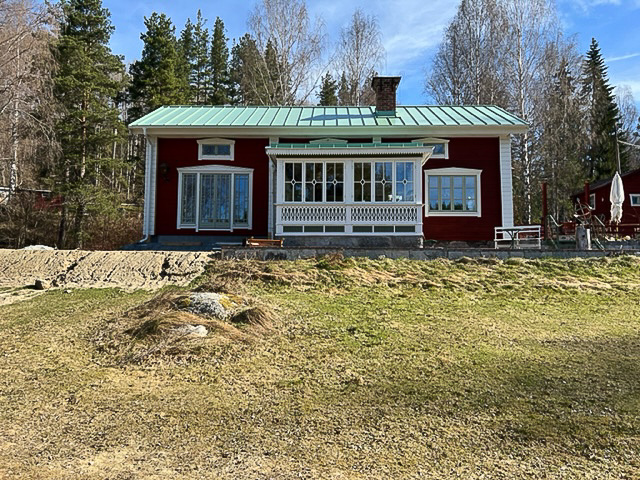 Röd villa med inglasad veranda och stora fönsterpartier som ger ljus och utsikt längs fasaden