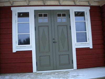 Pardörr med tydlig spegelindelning och klassisk symmetri, inramad av sidofönster.