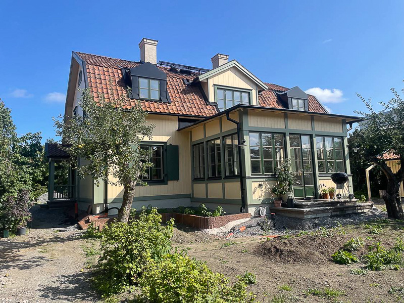 Hus med glasveranda där en hel vägg består av höga fönsterpartier med smala spröjs och stora glasrutor.