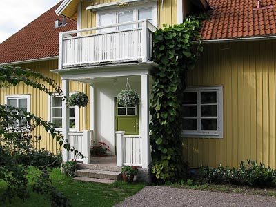 Husfasad med ny entrédörr i halvfransk stil och glasruta med spröjs i rutnät.