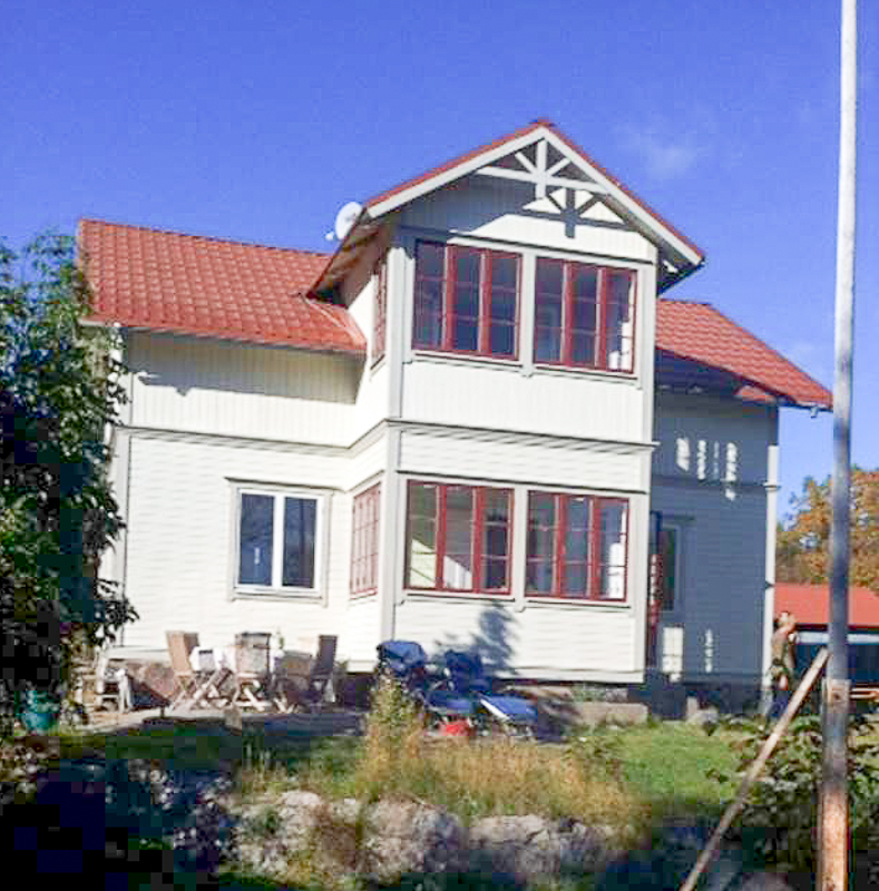 Vitt hus med röda detaljer och flera fönster på fasaden.
