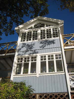 Tillbyggnad med spröjsade fönster i rutnät och en liten romb/diagonal-detalj i överkant.