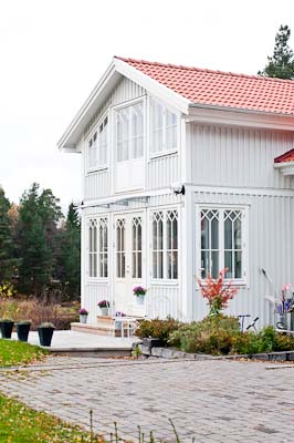Översiktsbild av hus med veranda, spröjsade fönster och kryss/diagonal-spröjs i överkant.