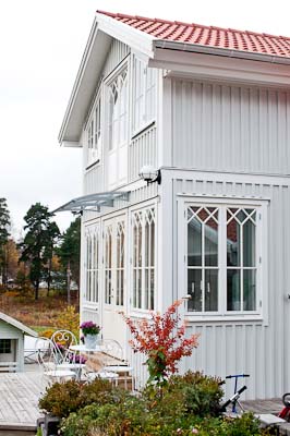 Verandafasad med spröjsade partier och kryss/rombmönster i de övre fälten.