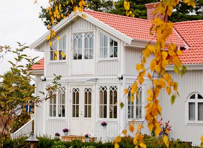 Vit veranda med spröjsade fönster där överdelen har kryss/diagonal-spröjs som bildar romber.