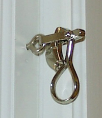 Närbild av kromad fönsterhasp med ringformat handtag på vit karm.