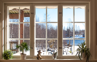 Fönster med spröjs och lösa innerbågar, fönsterbräda med krukväxter och vinterutsikt.